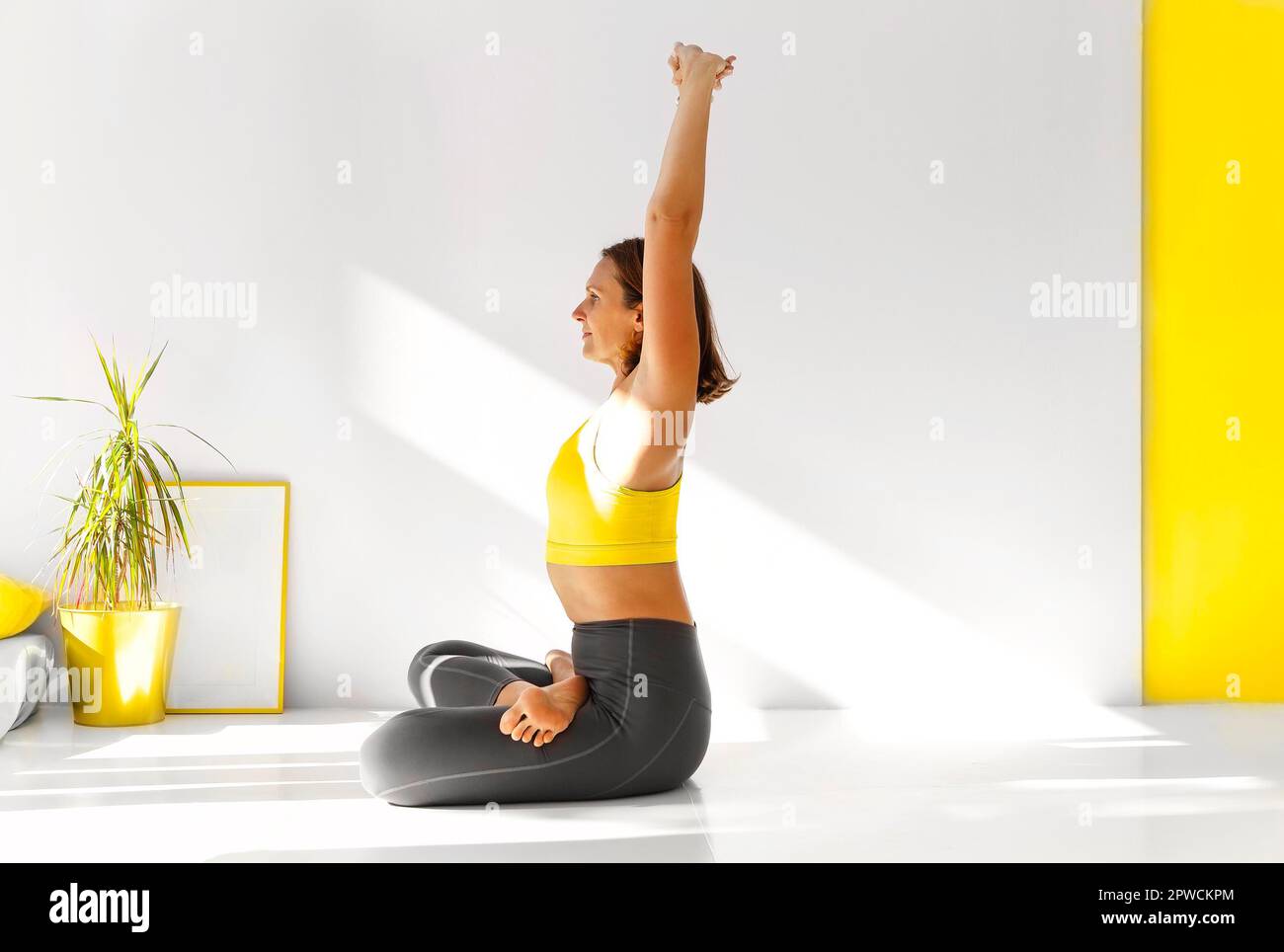 Vue latérale de la femme calme dans les vêtements de sport pratiquant le yoga dans la posture Firefly tout en équilibrant les bras et en regardant loin Banque D'Images