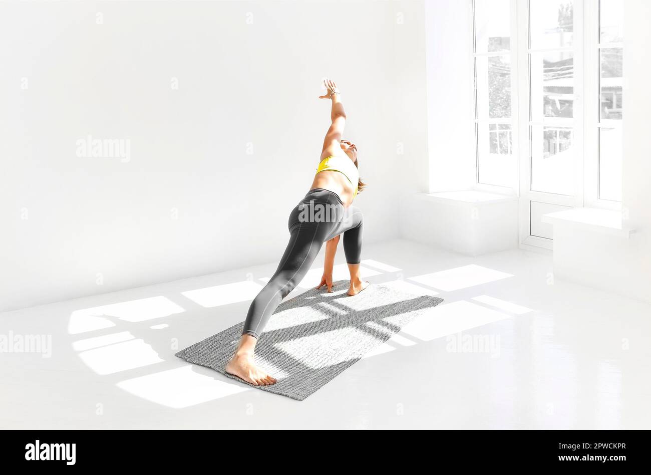 Vue latérale de la femme calme dans les vêtements de sport pratiquant le yoga Pompier pose tout en équilibrant les bras sur le tapis et en regardant loin Banque D'Images