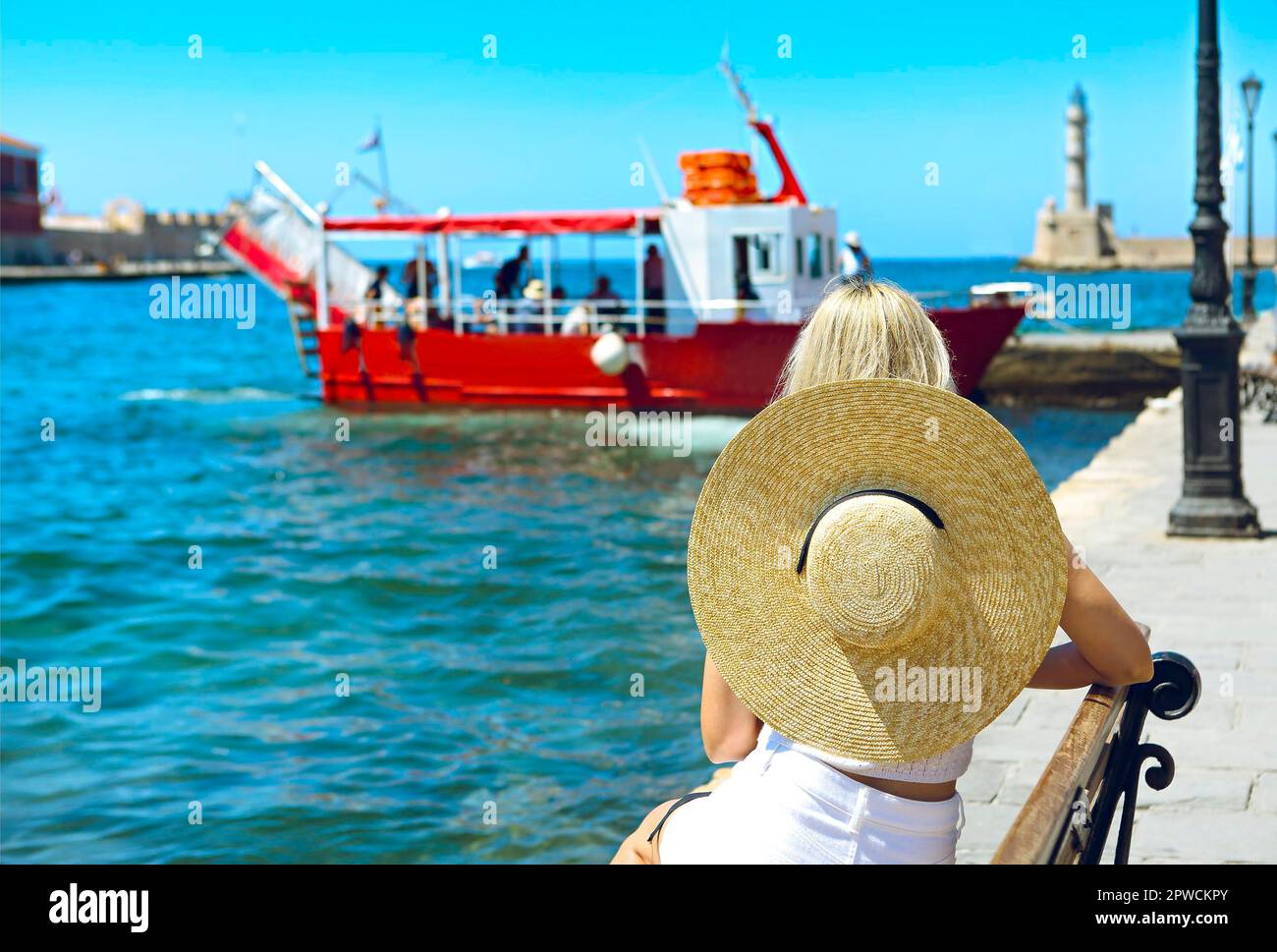 Jeune femme blonde dans un grand chapeau profitant de la vue magnifique sur le port de Chania dans le style vénitien. Histoire Architecture Voyage. Chania, Crète. Banque D'Images