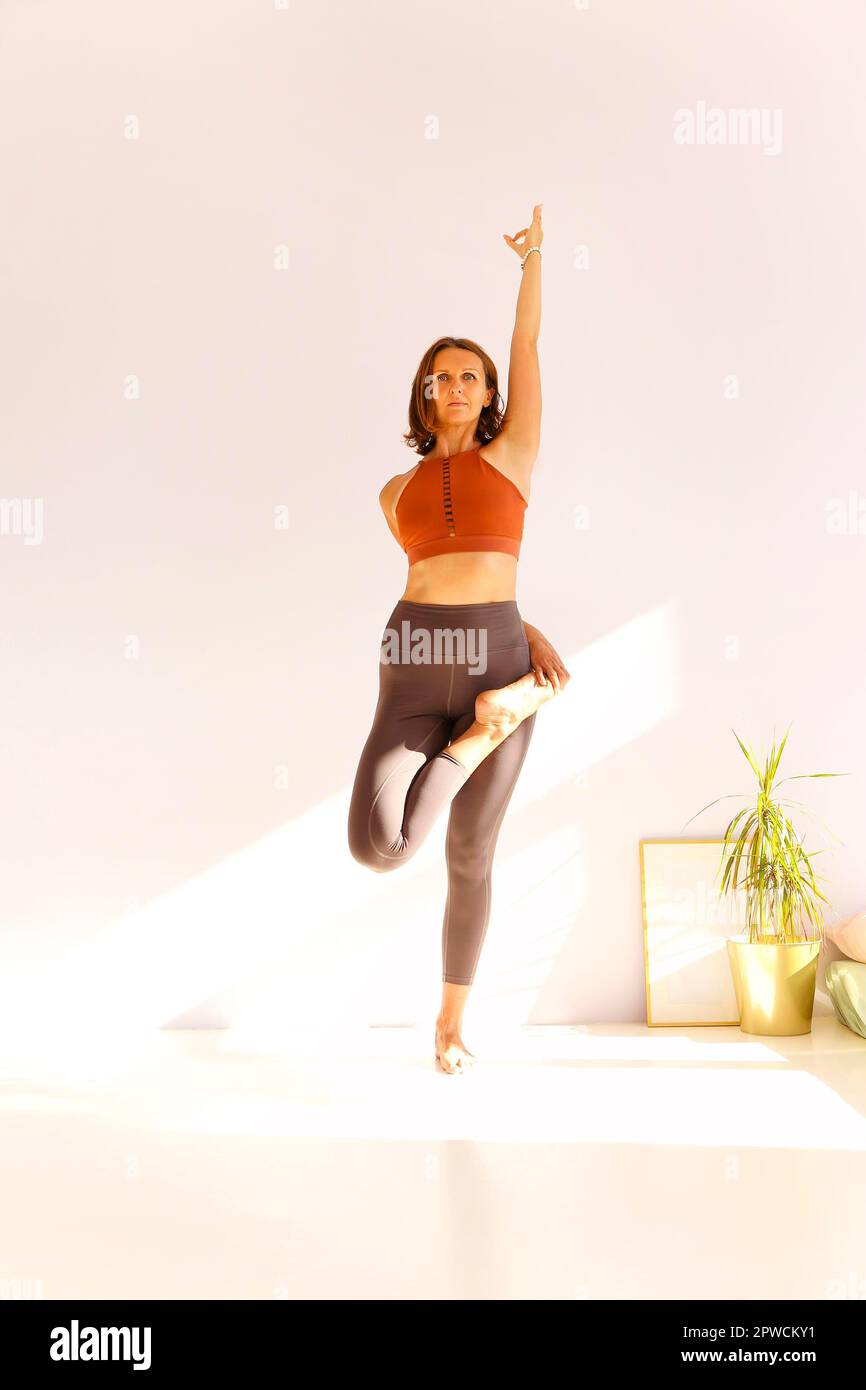 Vue latérale de la femme calme dans les vêtements de sport pratiquant le yoga Pompier pose tout en équilibrant les bras sur le tapis et en regardant loin Banque D'Images