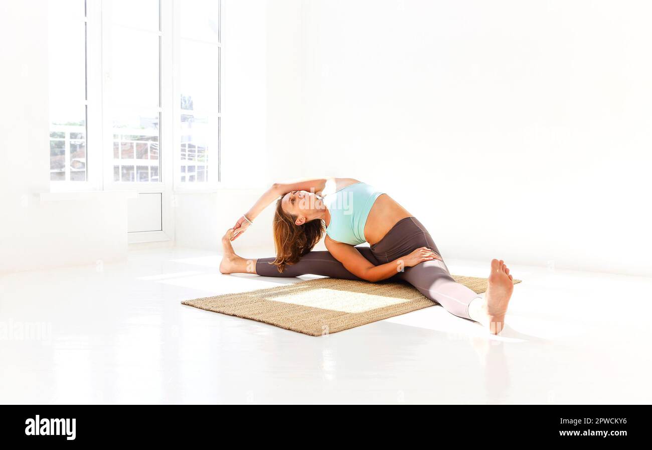 Vue latérale de la femme calme dans les vêtements de sport pratiquant le yoga Pompier pose tout en équilibrant les bras sur le tapis et en regardant loin Banque D'Images