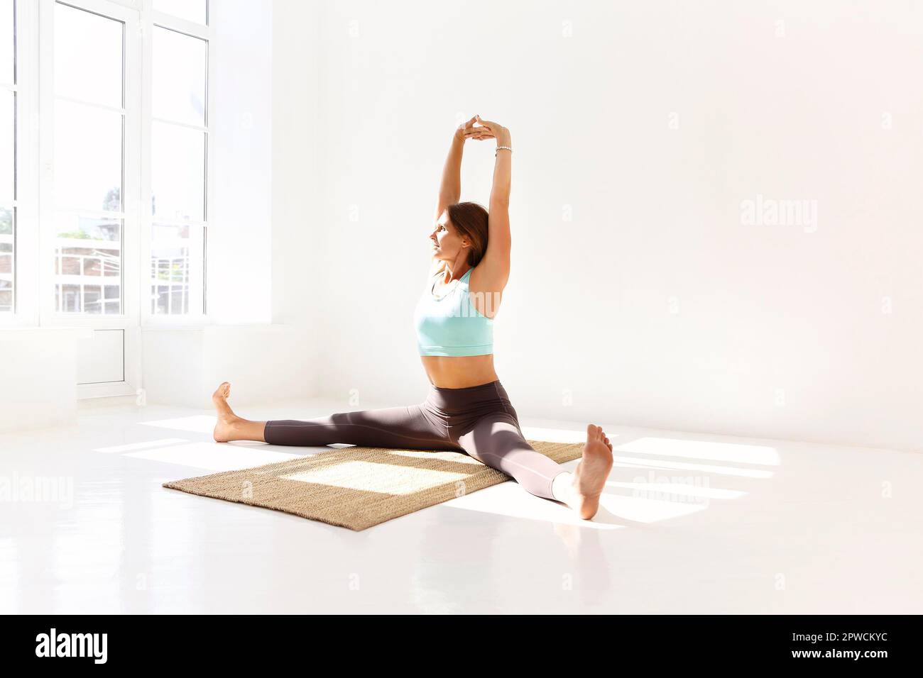 Vue latérale de la femme calme dans les vêtements de sport pratiquant le yoga Pompier pose tout en équilibrant les bras sur le tapis et en regardant loin Banque D'Images