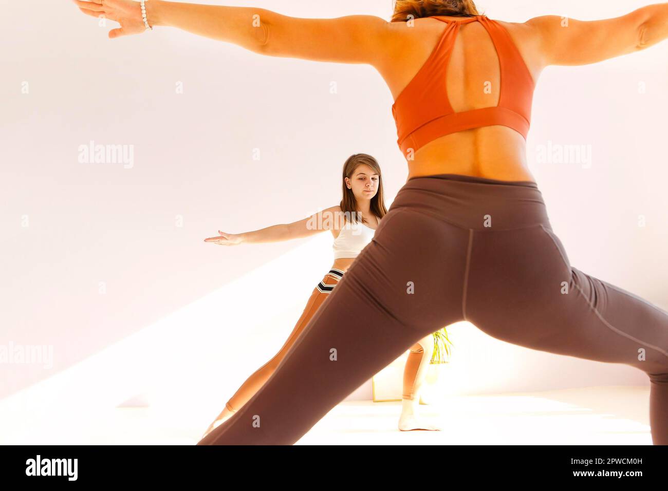 Femme adulte aidant les jeunes femmes dans les vêtements de sport avec faire du yoga En posture de triangle et bras d'étirement Banque D'Images