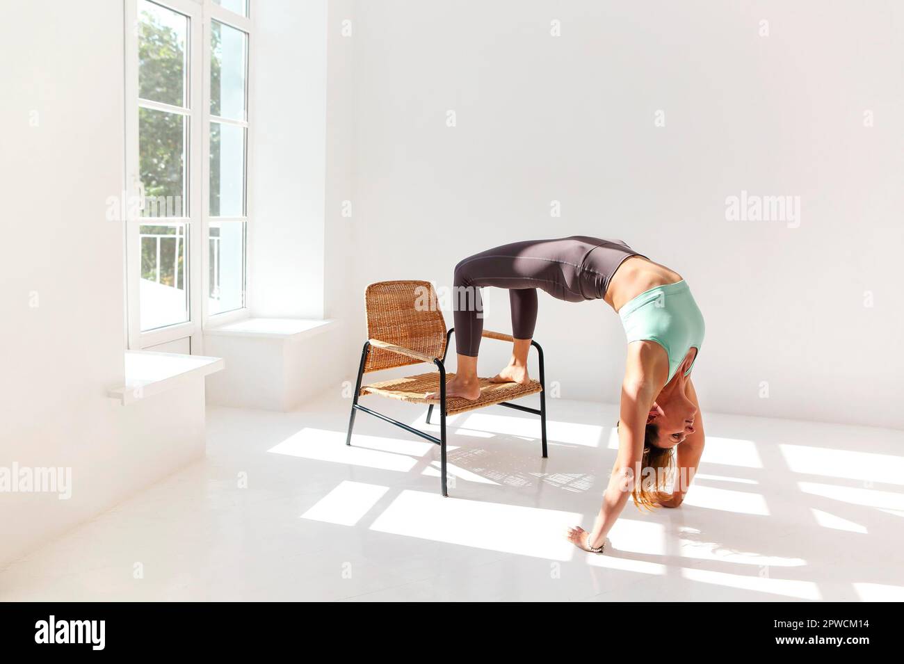 Vue latérale de la femme calme dans les vêtements de sport pratiquant le yoga Pompier pose tout en équilibrant les bras sur le tapis et en regardant loin Banque D'Images