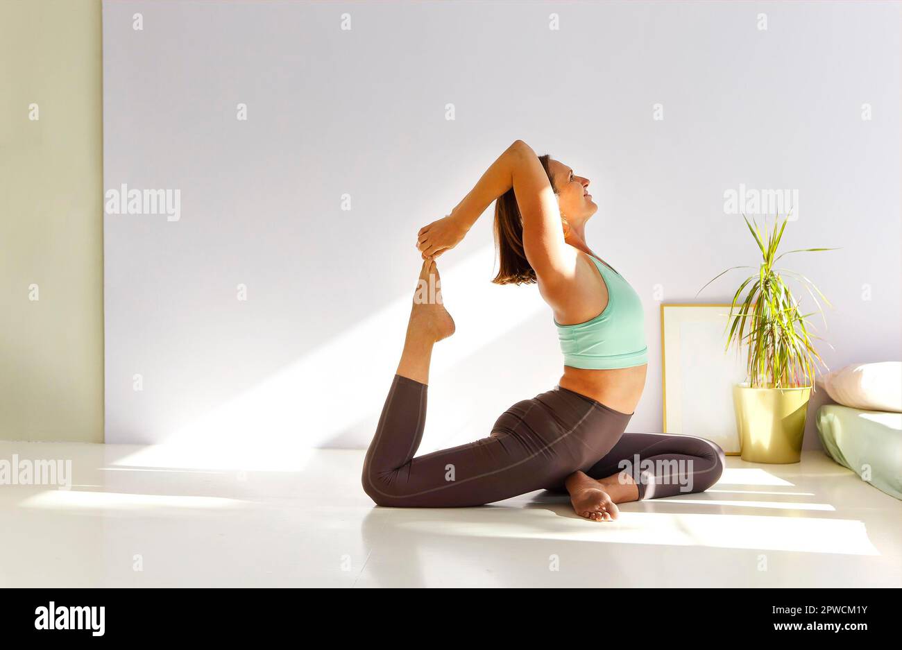 Vue latérale de la femme calme dans les vêtements de sport pratiquant le yoga Pompier pose tout en équilibrant les bras sur le tapis et en regardant loin Banque D'Images