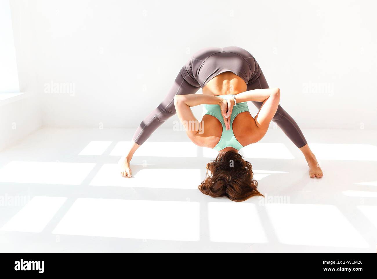 Vue latérale de la femme calme dans les vêtements de sport pratiquant le yoga pendant equilibrage sur les bras sur le tapis et vue à l'écart Banque D'Images