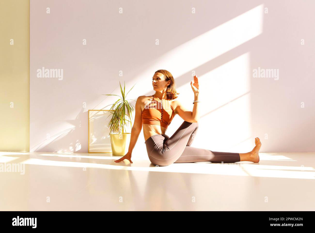 Vue latérale de la femme calme dans les vêtements de sport pratiquant le yoga dans la posture Firefly tout en équilibrant les bras sur le tapis et en regardant loin Banque D'Images