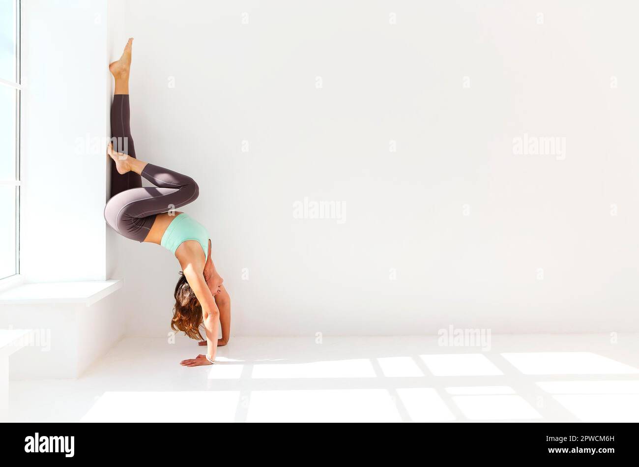 Vue latérale de la femme calme dans les vêtements de sport pratiquant le yoga dans la posture Firefly tout en équilibrant les bras et en regardant loin Banque D'Images