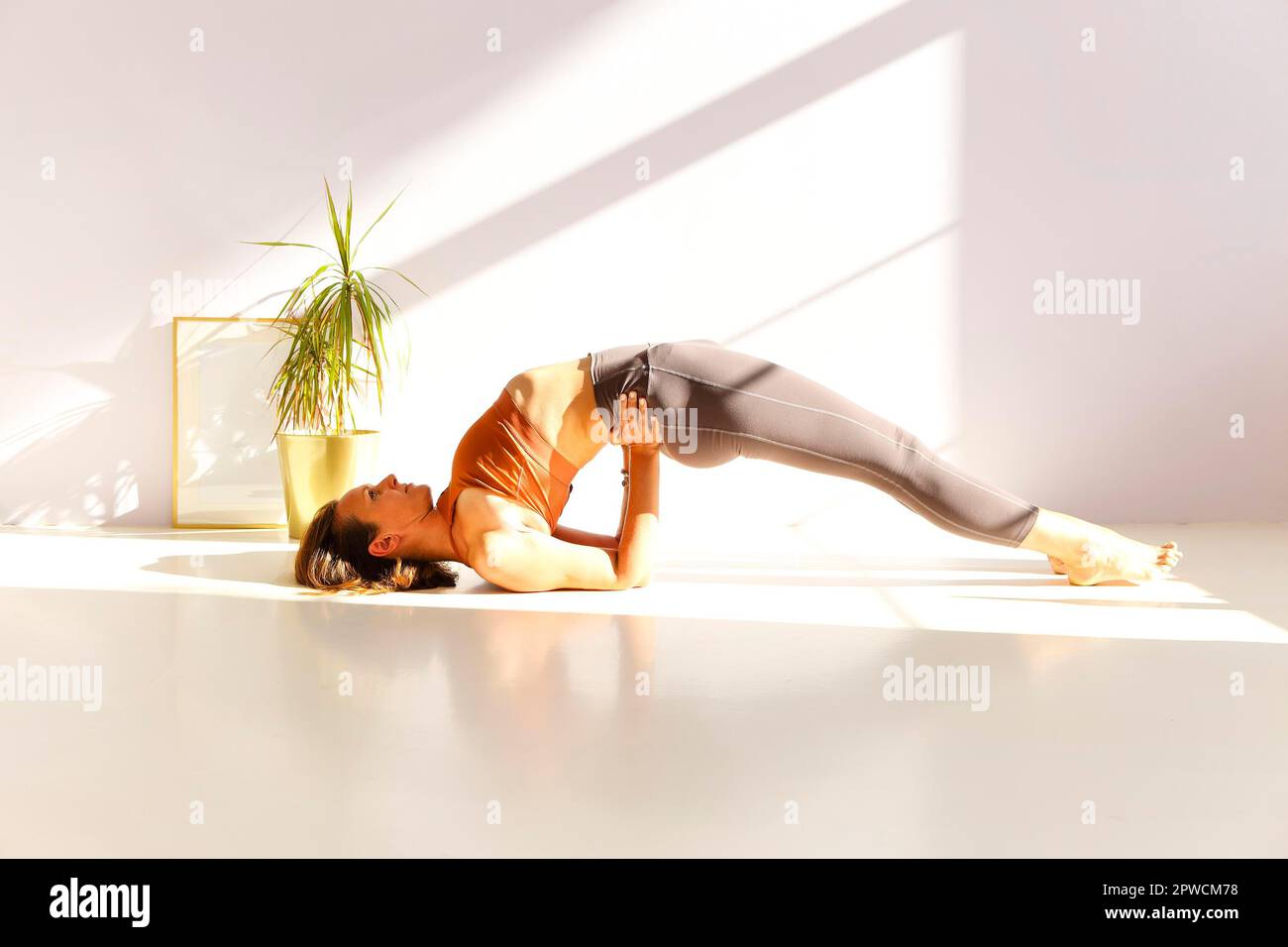 Vue latérale de la femme calme dans les vêtements de sport pratiquant le yoga dans la posture de Firefly tout en équilibrant sur les bras Banque D'Images