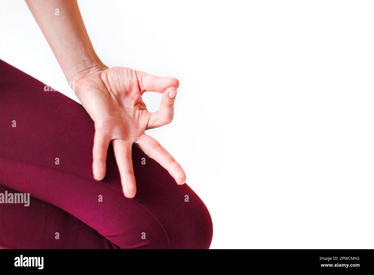 Une vue rognée de la femme méconnue dans les vêtements de sport avec les mains de mudra sur le tapis et faisant du yoga tout en pratiquant la pleine conscience Banque D'Images
