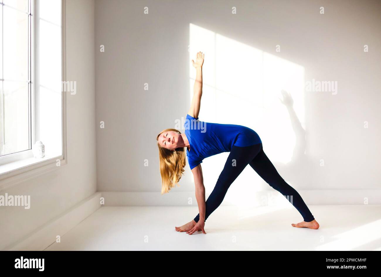 Calme femme dans les vêtements de sport pratiquant le yoga dans la posture de Firefly tout en équilibrant et en regardant loin Banque D'Images