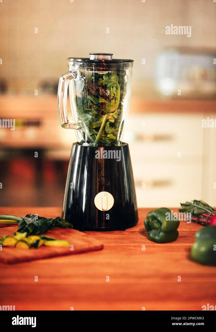 Gros plan de la machine de mixeur smoothie aux légumes verts dans la  cuisine avec feuilles de chou vert à l'intérieur prêtes pour le processus  de broyage. Concept de régime alimentaire sain