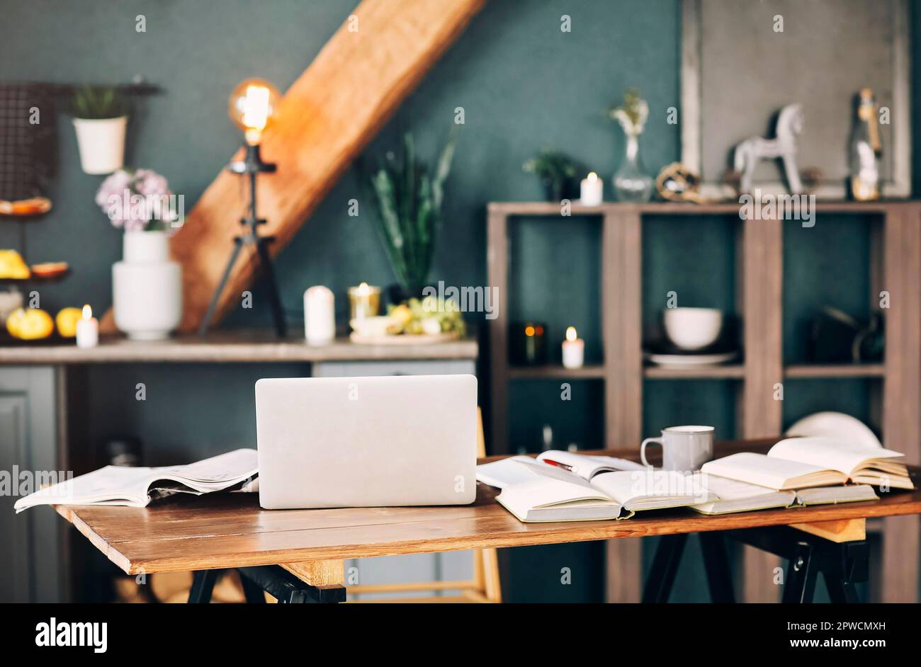 Manuel ouvert avec stylo, ordinateur portable, pile de livres découverts les uns sur les autres, tasse de café sur table en bois dans le fond intérieur du salon. Banque D'Images