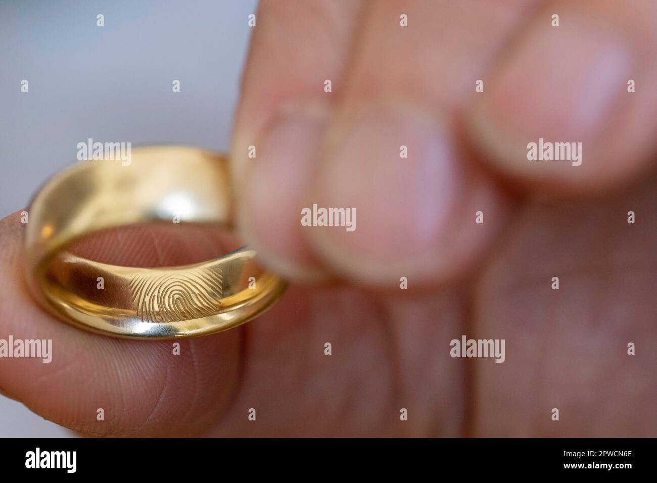 Doigt, main, bague de mariage dorée ou bague de mariage avec empreinte digitale gravée Banque D'Images