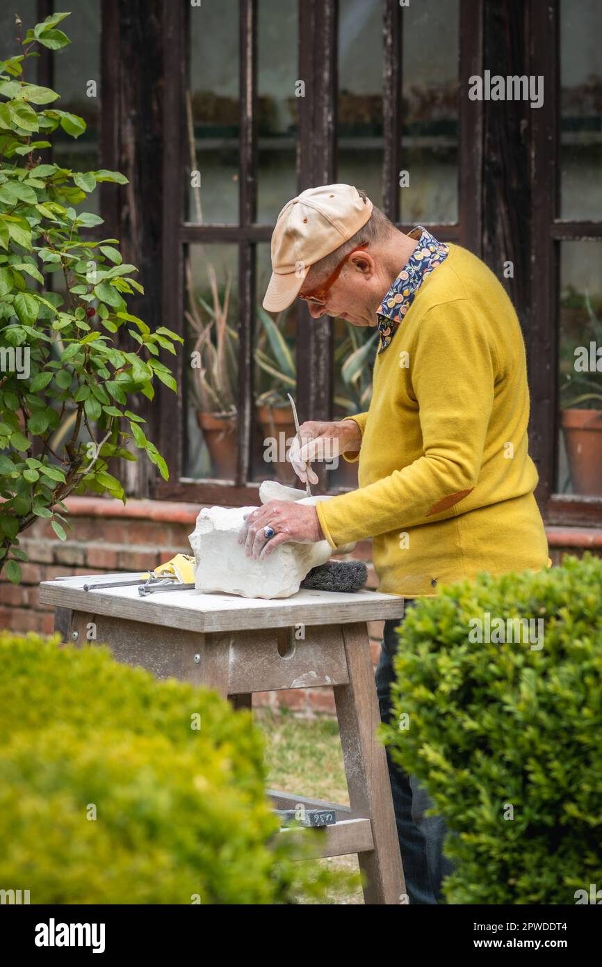 Homme sculptant une pierre lors d'une leçon de sculpture en plein air ou d'un cours dans le jardin botanique du château de San Sebastiano da po près de Turin, Piemonte, Italie Banque D'Images