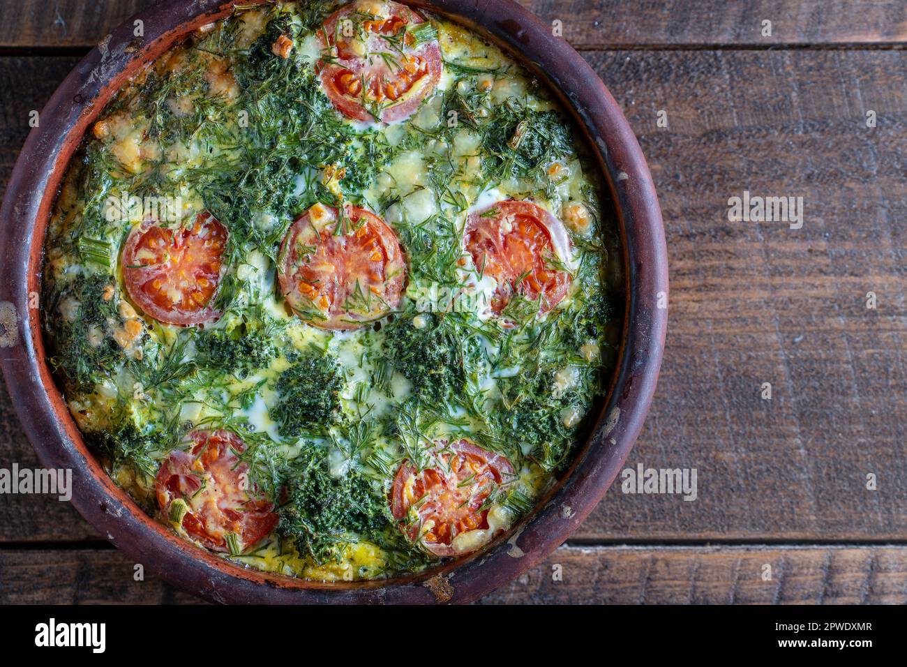 Bol en céramique avec frittata de légumes, simple nourriture végétarienne. Frittata avec oeuf, tomate, poivre, oignon, brocoli vert et fromage sur table en bois, clo Banque D'Images