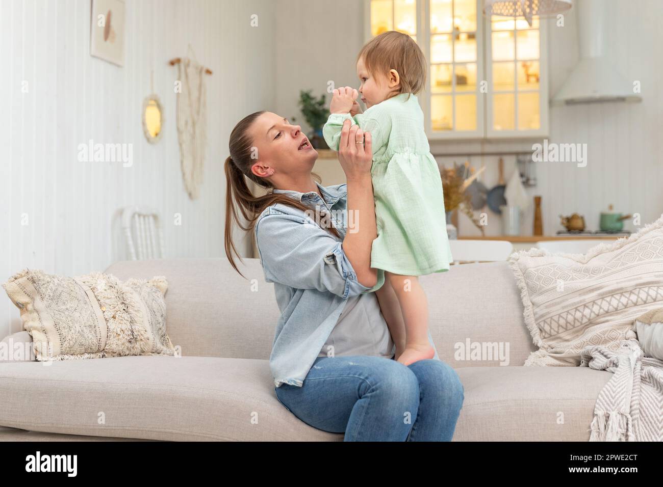 Bonne famille a la maison. La mere se leve dans l air petite fille enfant. Maman et bebe fille jouant en s amusant ensemble a la maison. La mere cale bebe avec le soin