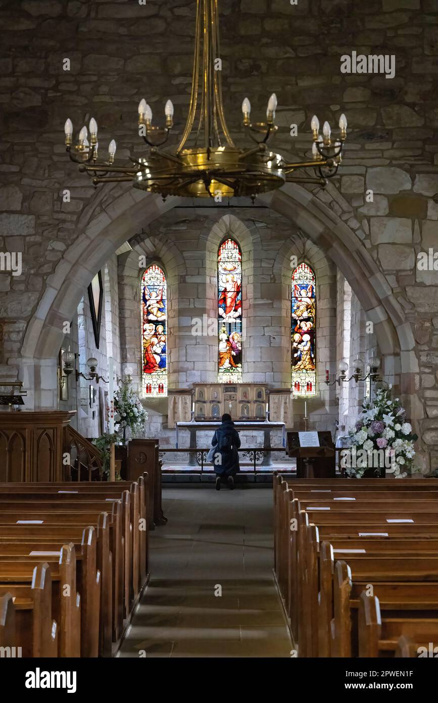 Une femme priant dans l'église à l'autel de l'église, l'église St Marys, Lindisfarne, l'île Sainte Northumberland Royaume-Uni Banque D'Images