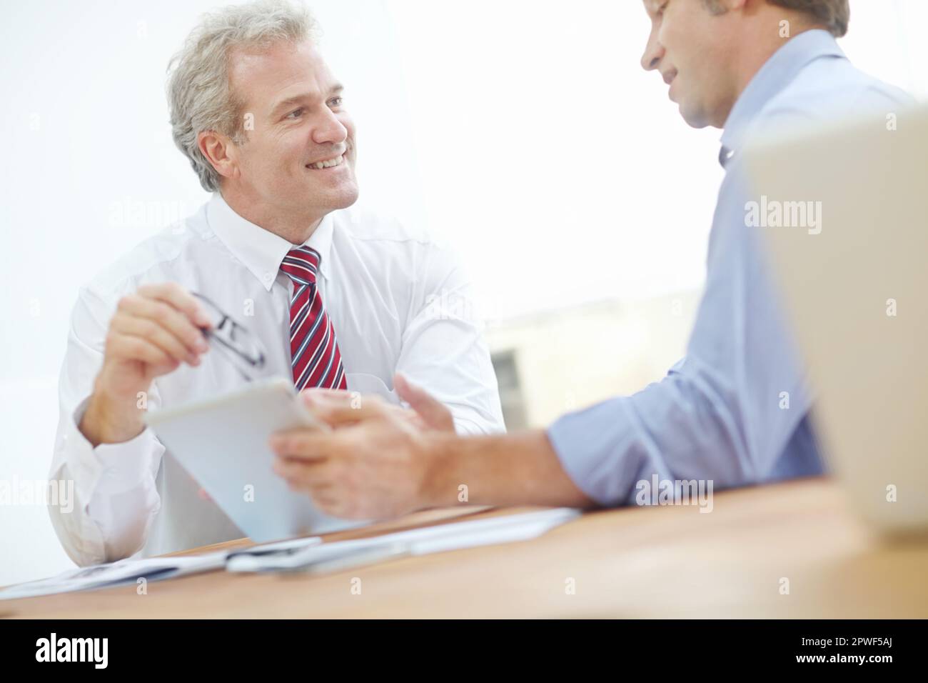 J'aime ces développements récents. Deux associés d'affaires de sexe masculin assis à un bureau pour une réunion. Banque D'Images