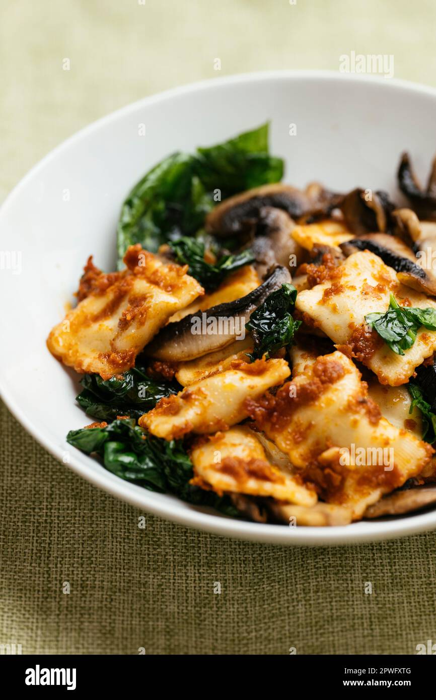 Raviolis végétaliens aux champignons, aux épinards et à la sauce tomate séchée au soleil. Banque D'Images