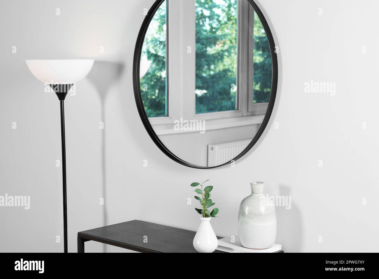 Miroir rond élégant sur un mur blanc sur une table dans la chambre Banque D'Images