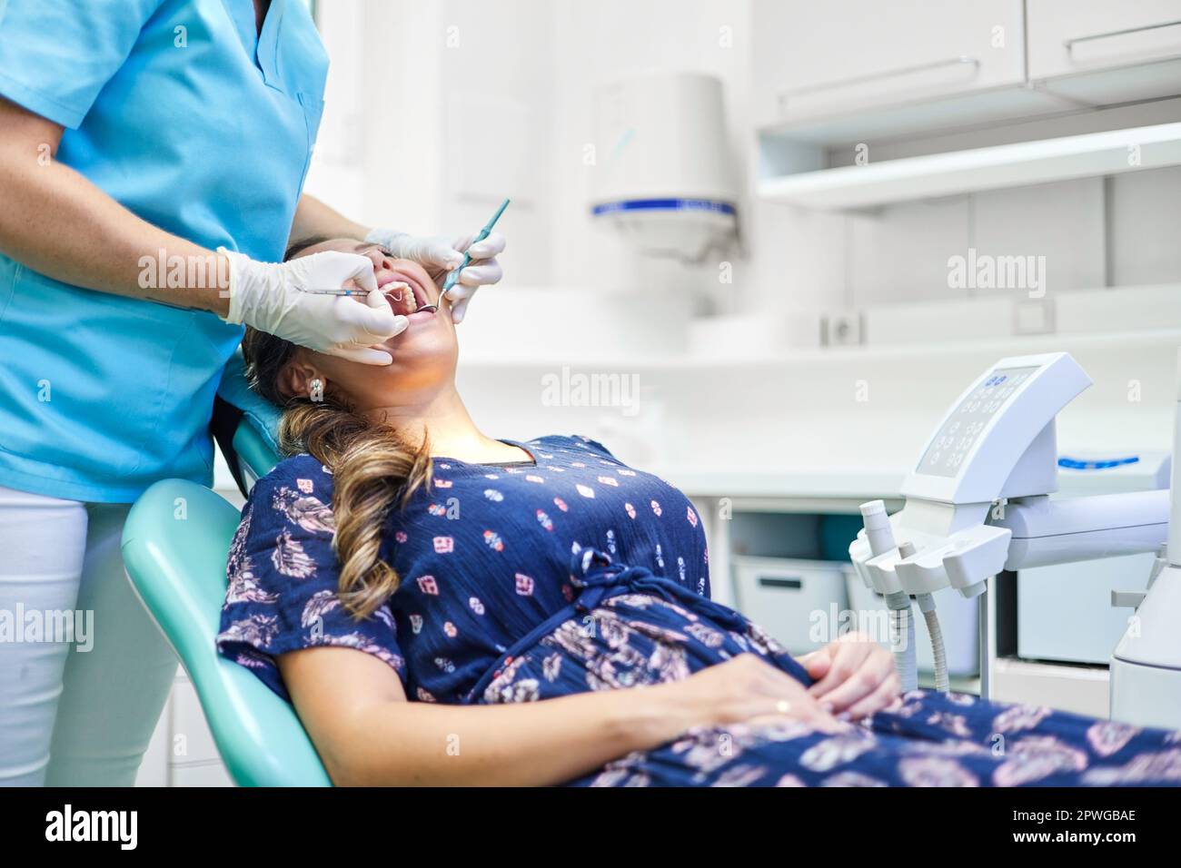 Crop dentiste en uniforme et gants en latex utilisant la sonde et le miroir pour examiner les