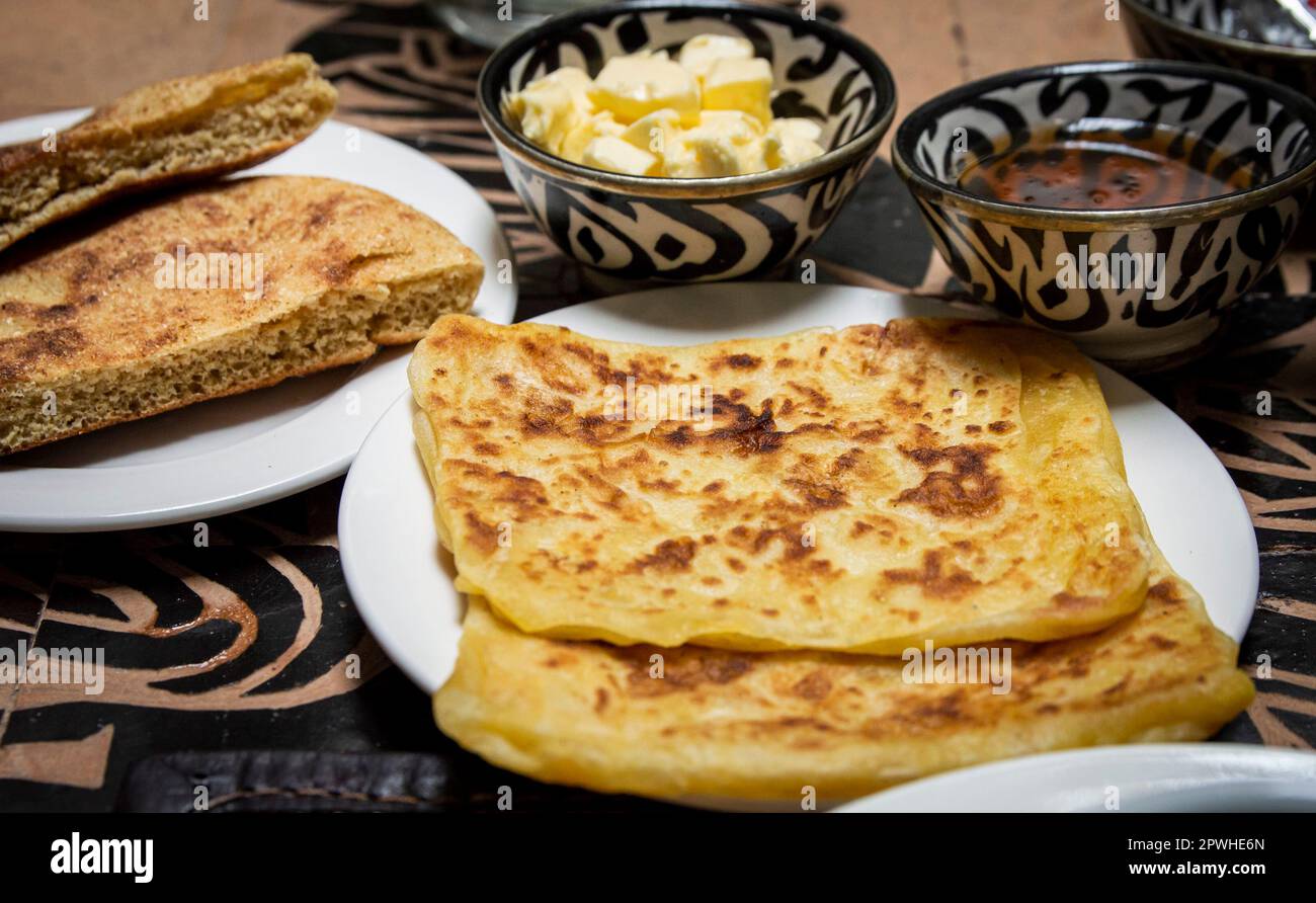 Petit-déjeuner marocain traditionnel avec crêpes, pain, beurre et miel sur la table à manger Banque D'Images