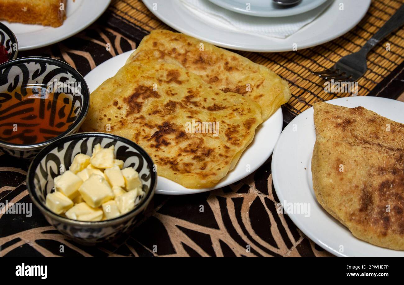 Petit-déjeuner marocain traditionnel avec crêpes, pain, beurre et miel sur la table à manger Banque D'Images