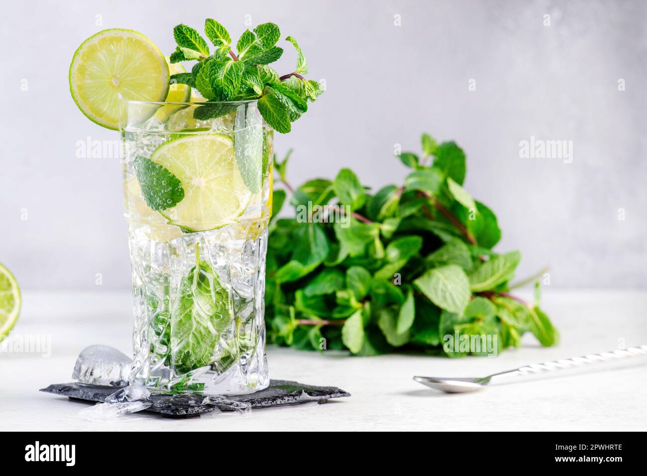 Cocktail d'été Mojito avec citron vert, rhum blanc, soda, sucre de canne,  menthe, et glace en verre à haute bille sur fond gris. Outils à barre  d'acier Photo Stock - Alamy