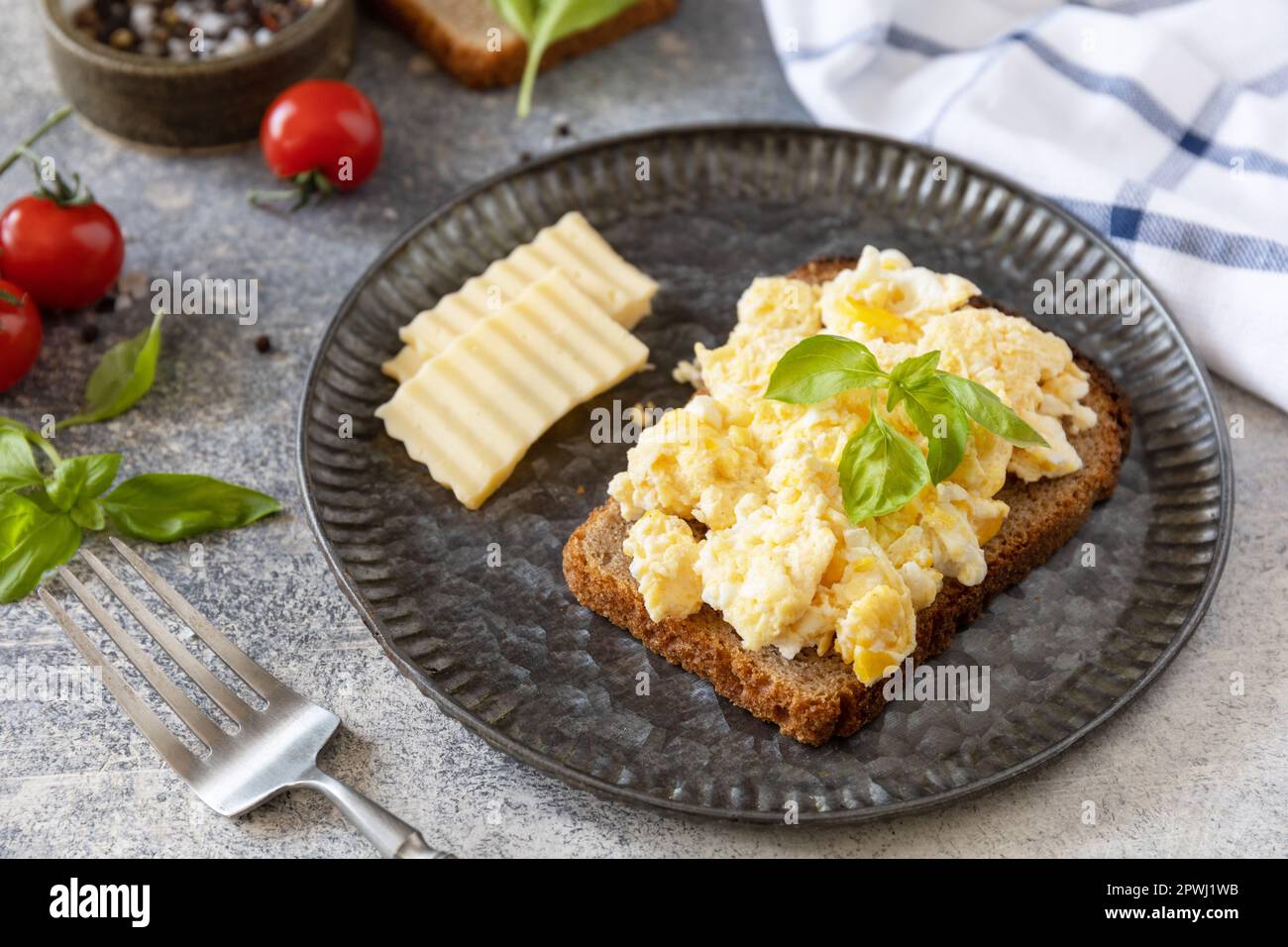 Œufs brouillés sur du pain à grains entiers sur une table en pierre. Petit-déjeuner ou brunch maison - œufs brouillés. Banque D'Images