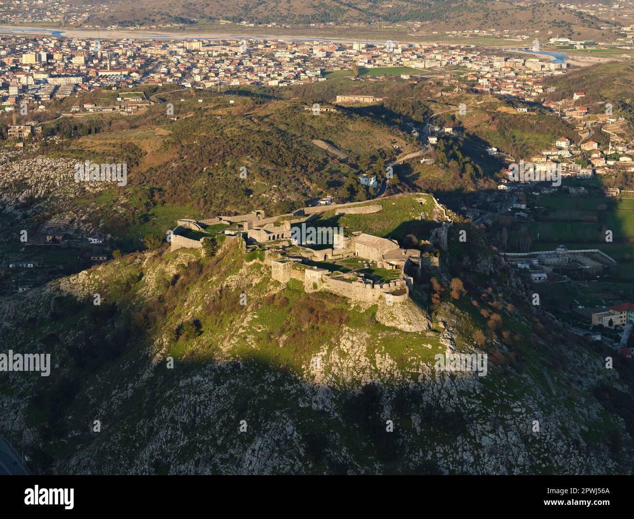 VUE AÉRIENNE. Château de Rozafa dans la lumière du soir surplombant la ville de Shkodër. Comté de Shkodër, Albanie. Banque D'Images