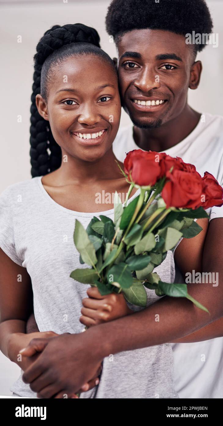 Elle mérite des fleurs tous les jours de la semaine. une jeune femme tenant un bouquet de roses rouges tout en étant debout avec son petit ami à la maison Banque D'Images