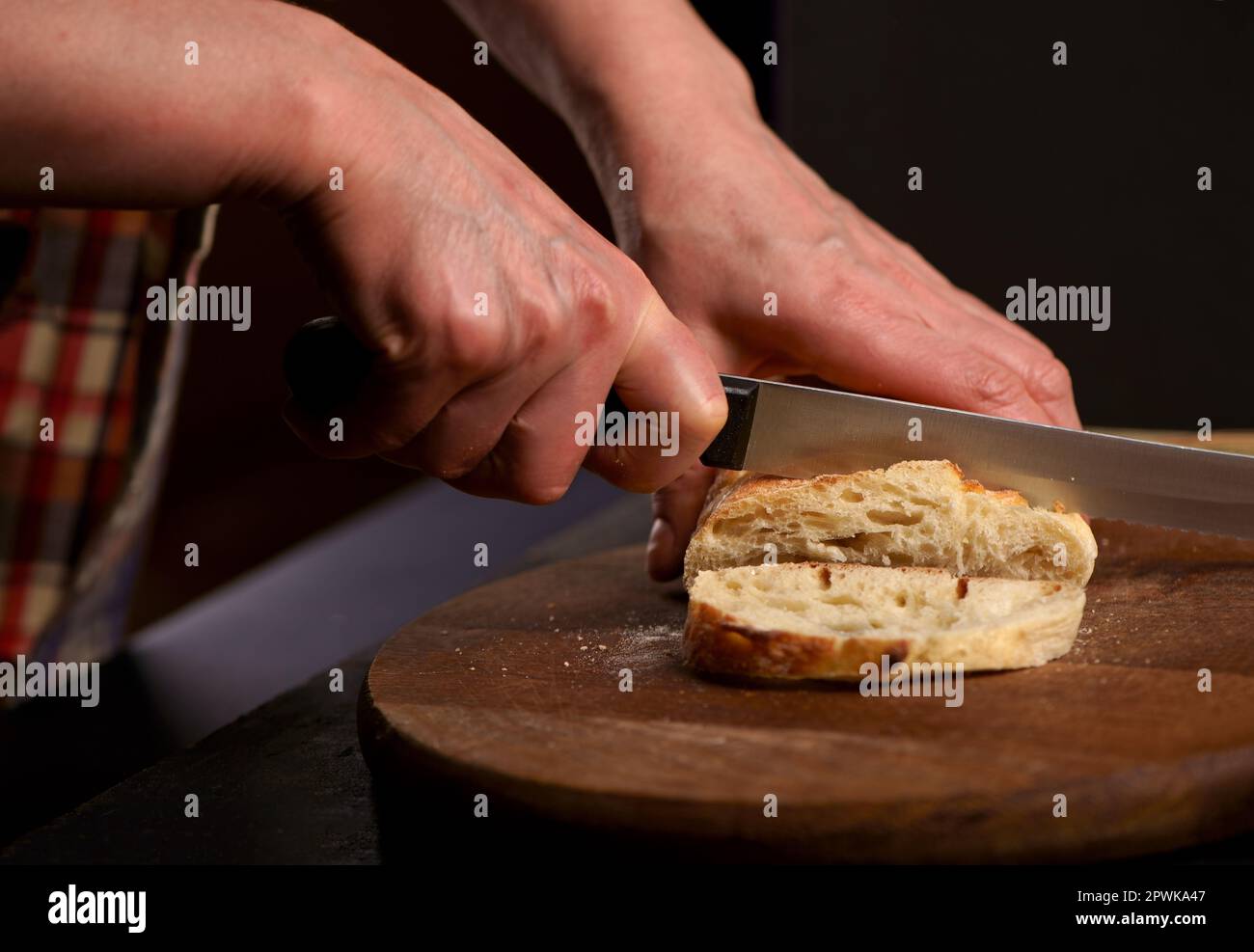 Le concept de saine alimentation et de boulangerie traditionnelle. Vue avant Pain de grain entier mis sur la plaque de bois de cuisine avec un chef tenant le couteau pour couper. Frais br Banque D'Images