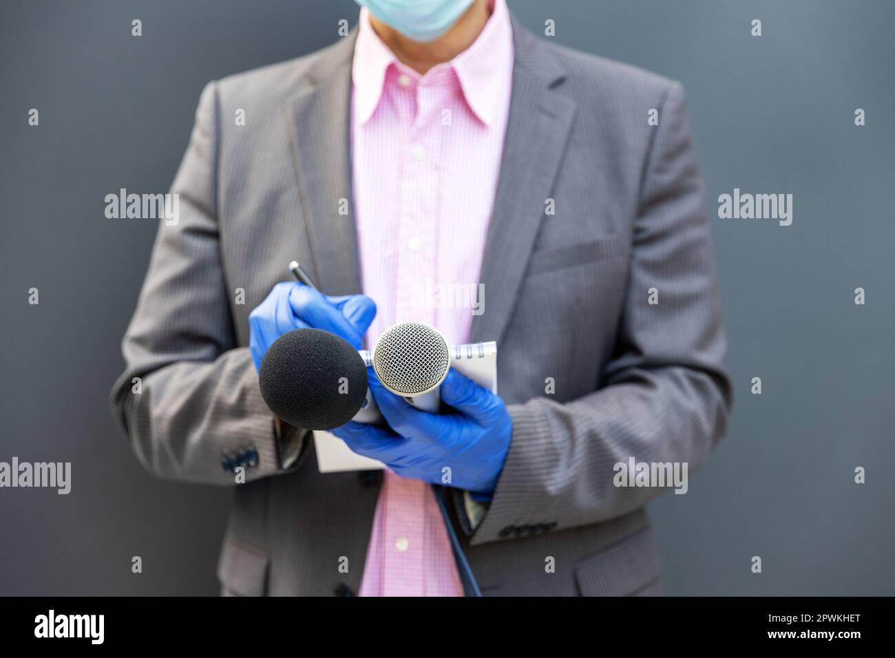 Journaliste à la conférence de presse portant des gants de protection et un masque facial Contre le coronavirus la maladie COVID-19 tenant des notes d'écriture de microphone pendant le vir Banque D'Images