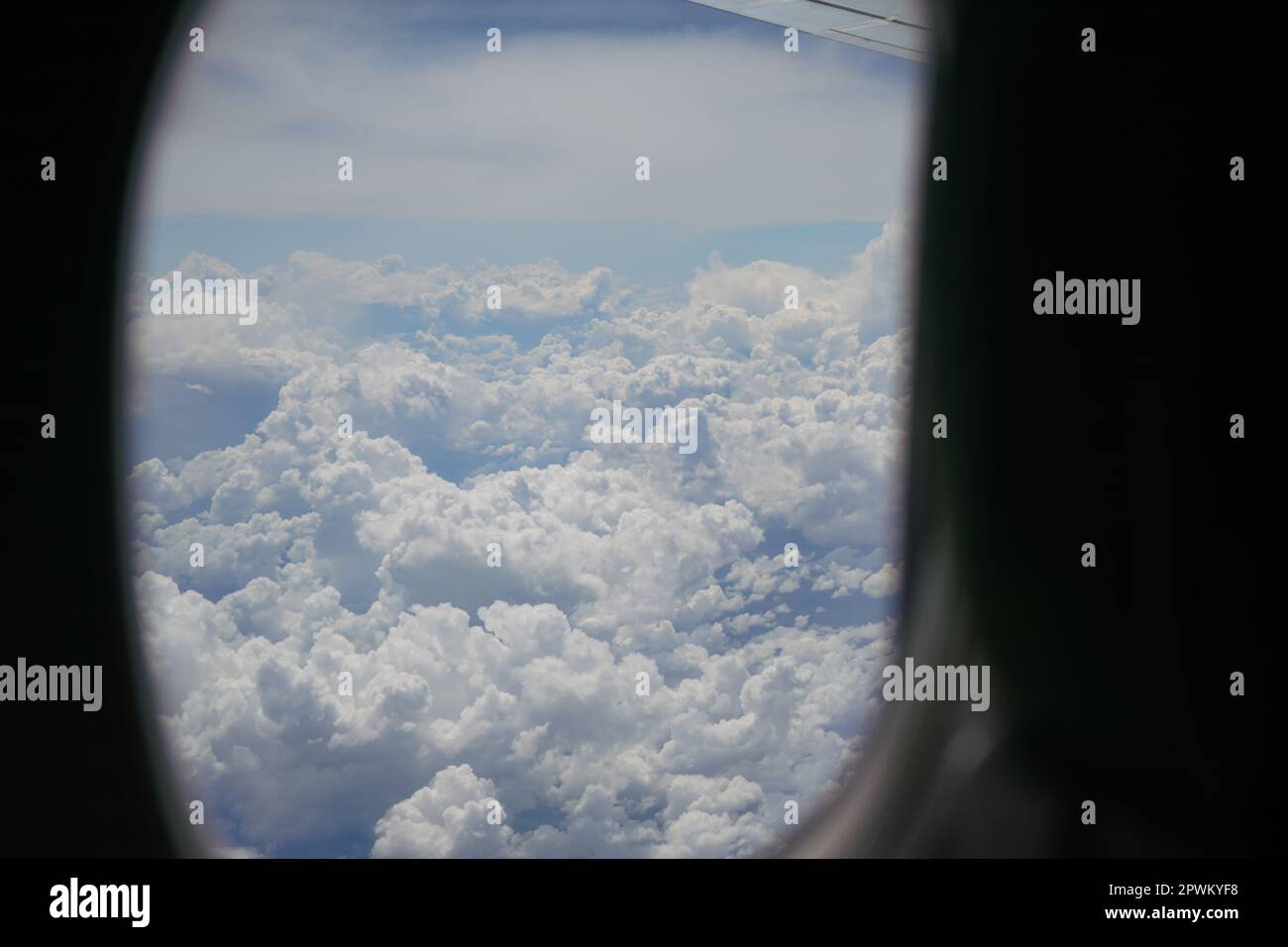 Vue depuis la fenêtre d'un avion commercial, nuages moelleux visibles en arrière-plan. Banque D'Images