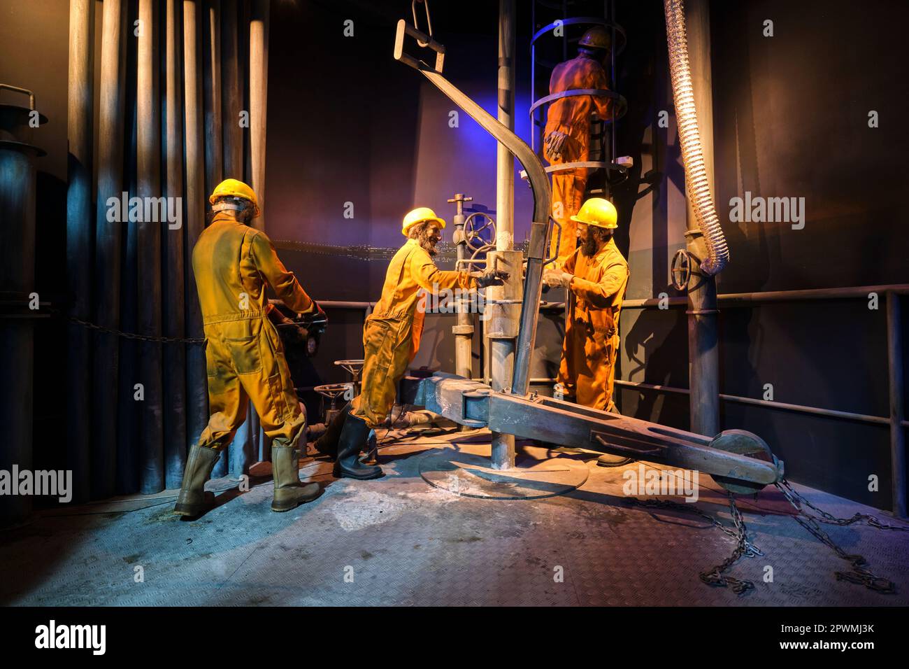 Un groupe d'engins de forage pétrolier, derick, ouvriers de puits dans des combinaisons orange, occupé à ajuster un tuyau de forage. Un diorama représentant une scène du passé des eau, à Abu Banque D'Images