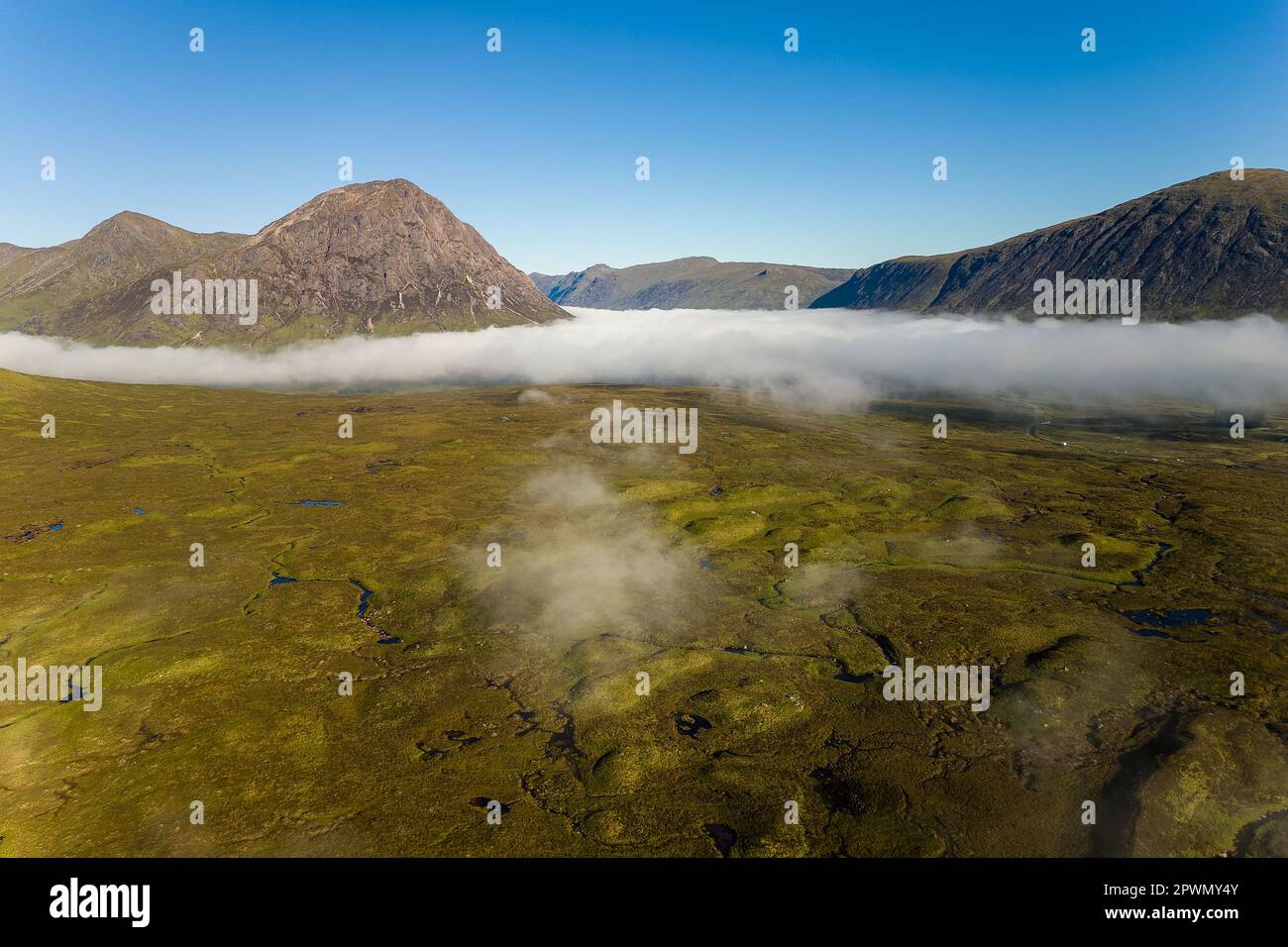 Vue aérienne des sommets de montagne qui s'élèvent au-dessus du brouillard de basse altitude dans une vallée déserte (Glencoe, Highlands, Écosse) Banque D'Images