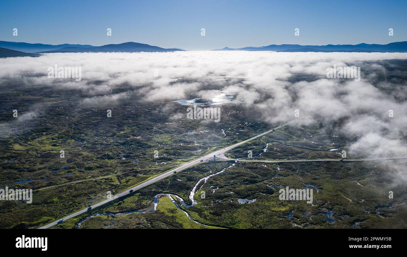 Vue aérienne d'une route traversant une vallée déserte avec un nuage bas et un brouillard au-dessus (Glen COE, Écosse) Banque D'Images