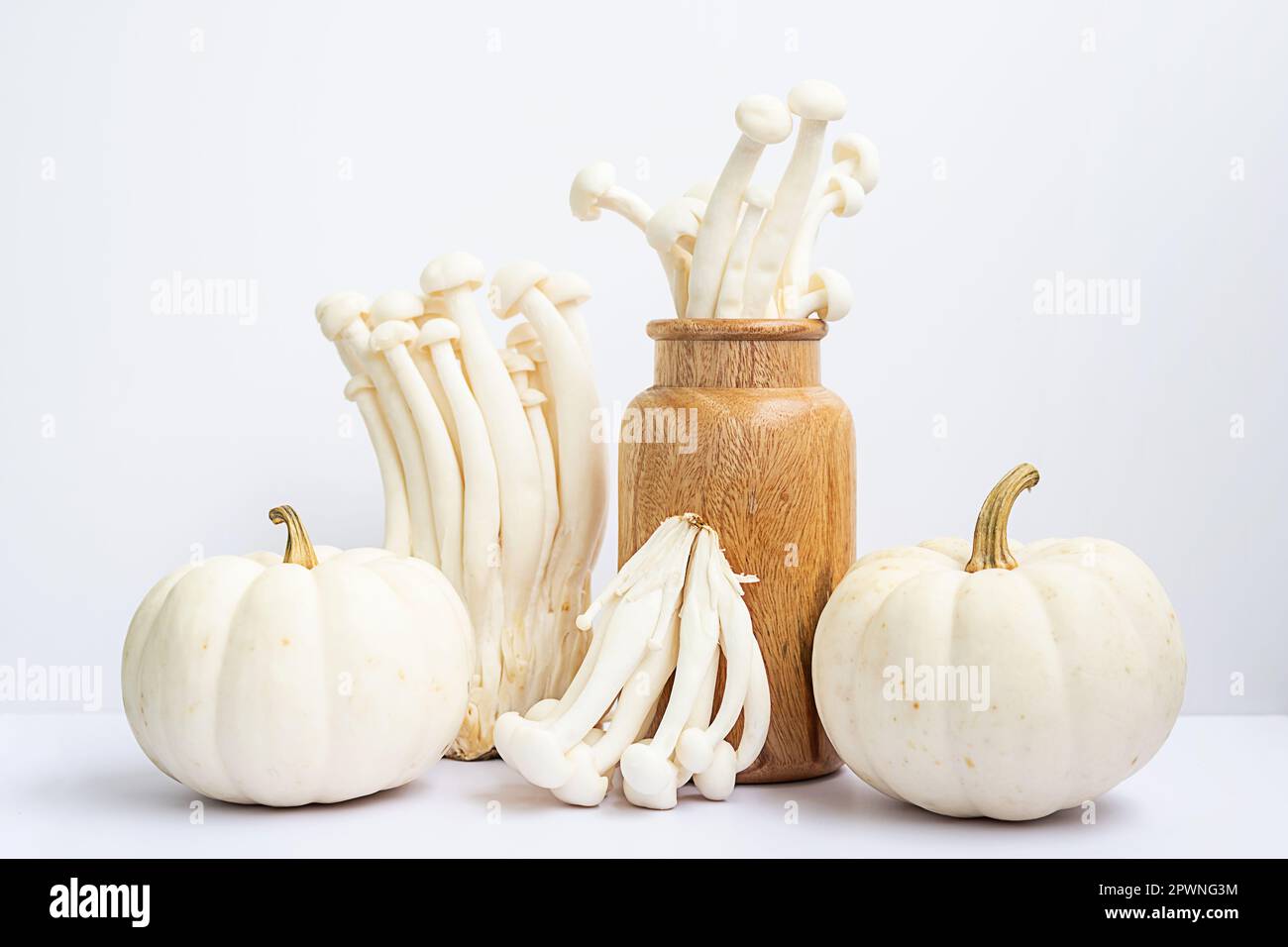 La durée de vie des légumes à l'automne. Petits citrouilles et champignons de hêtre dans un vase en bois. Banque D'Images
