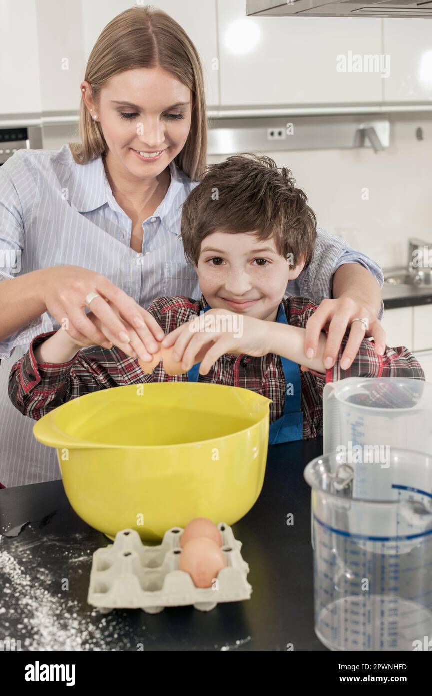 Un écolier craquant un œuf dans un bol de mélange de la classe économique domestique, Bavière, Allemagne Banque D'Images
