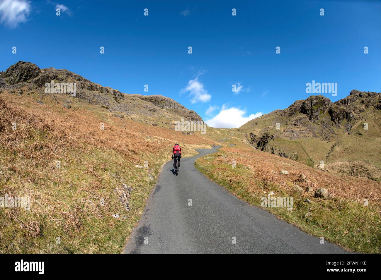 Un cycliste solitaire qui escalade la route la plus abrupte d'Angleterre, le col HardKnott, English Lake District. Banque D'Images