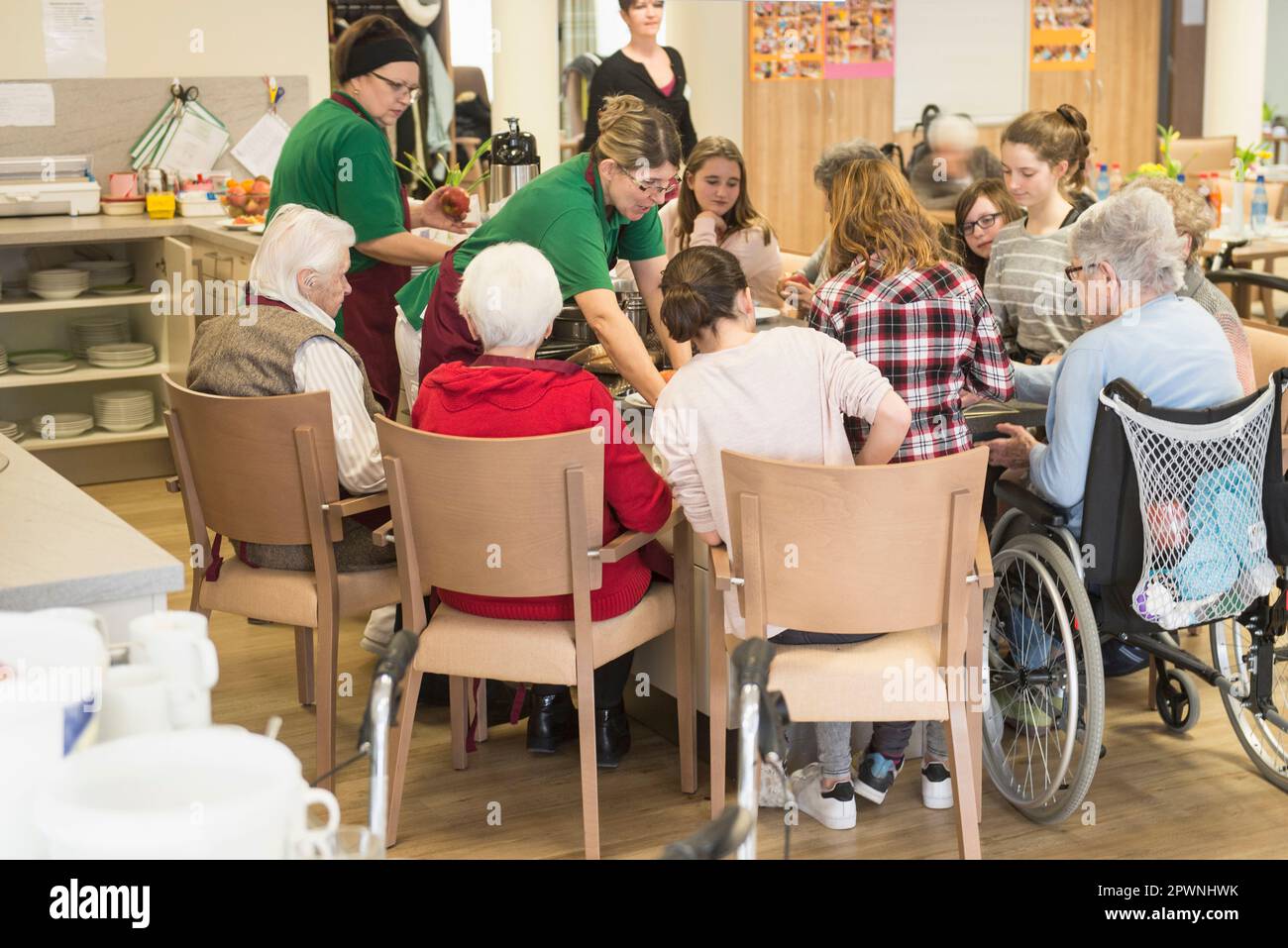 Personnel infirmier avec des femmes et des filles âgées préparant de la nourriture à la maison de repos Banque D'Images
