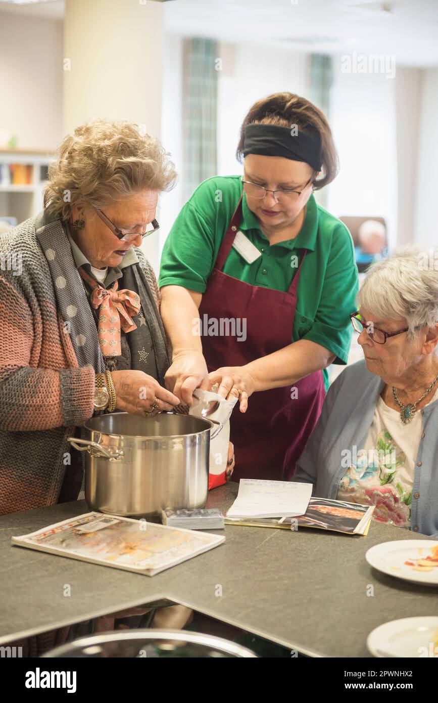 Infirmière avec des femmes âgées préparant de la nourriture à la maison de repos Banque D'Images