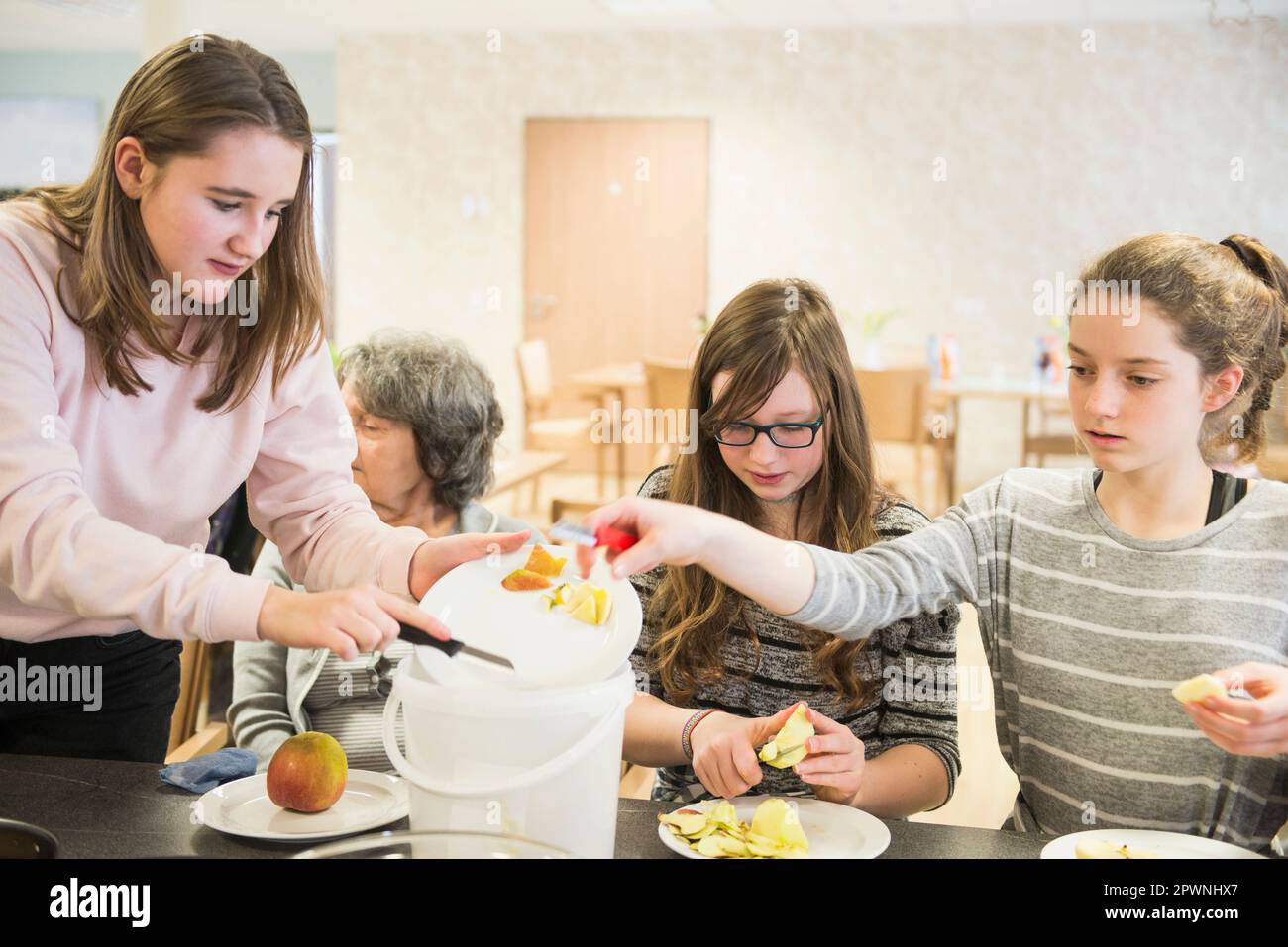 Femme âgée avec des filles épluchant la pomme à la maison de repos Banque D'Images