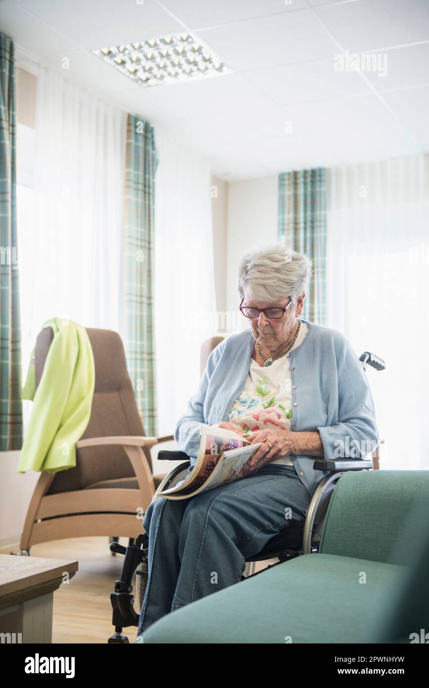 Femme âgée lisant le magazine à la maison de repos Banque D'Images