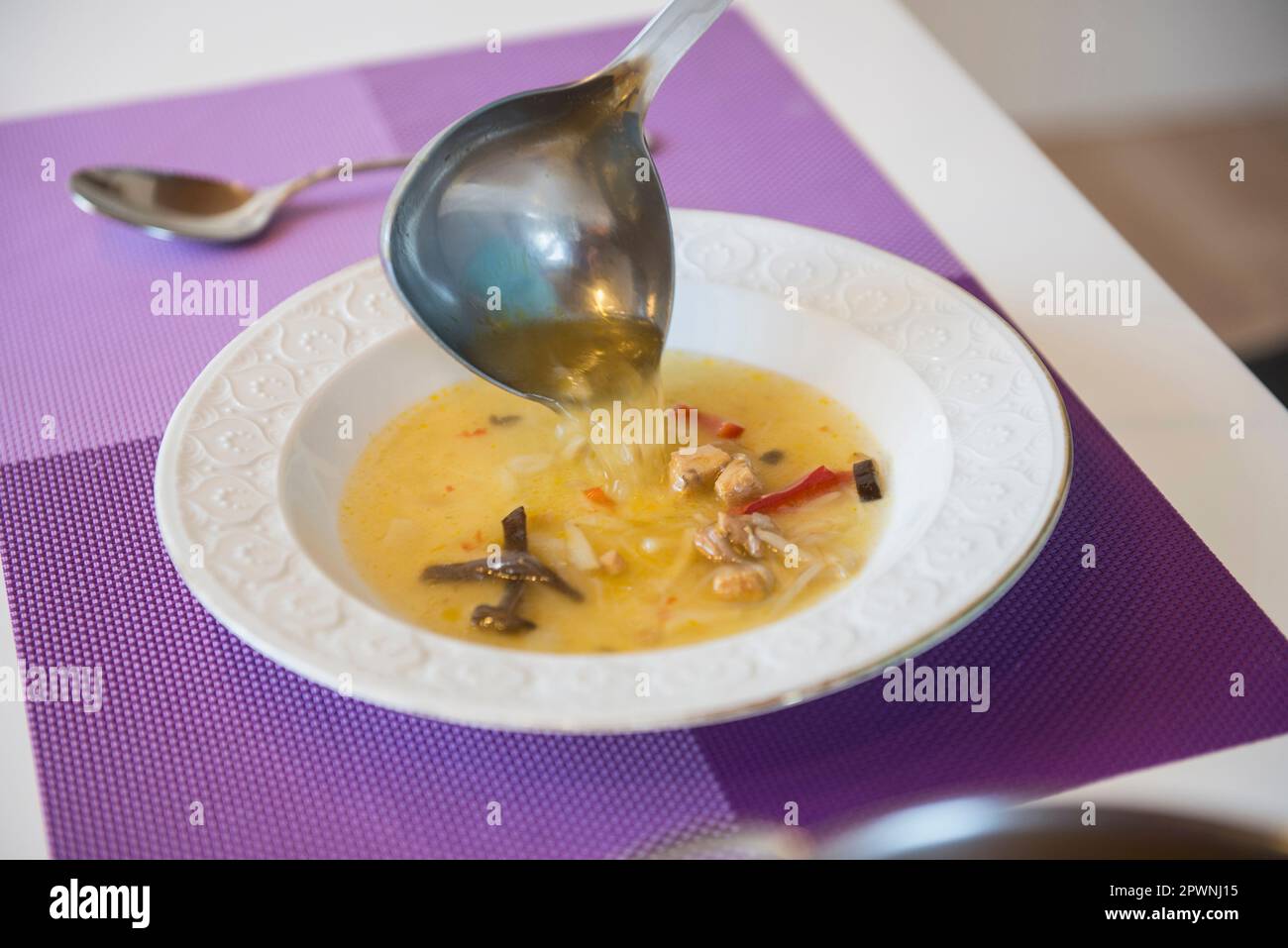 Soupe de nouilles versée dans une assiette à soupe sur la table à manger Banque D'Images