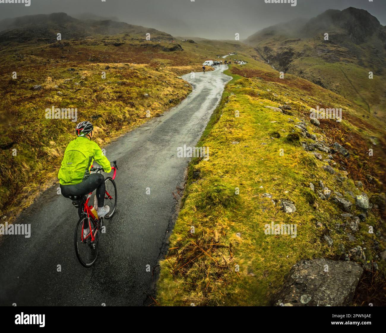 Cycliste de route grimpant au col de Hardnout par une journée humide et venteuse, Cumbria, Royaume-Uni. Banque D'Images