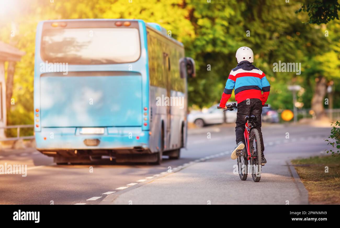 Garçon sur un vélo essayant de rattraper un bus bleu. Concept de l'enseignement à un enfant les règles de la route et de retour à l'école. Banque D'Images
