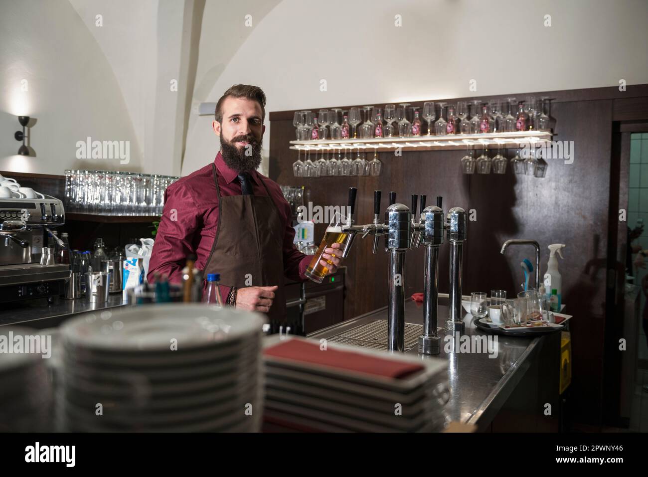 Portrait d'un jeune propriétaire remplissant un verre de bière au restaurant Banque D'Images