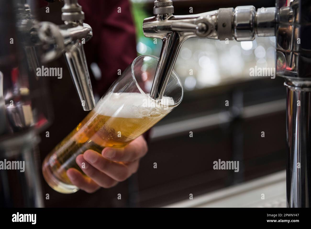 Mains au robinet de bière verser la bière dans un grand verre Banque D'Images